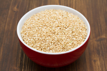 raw rice in red bowl on wooden background