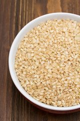 raw rice in red bowl on wooden background