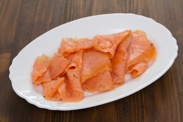 smoked salmon on white plate on wooden background