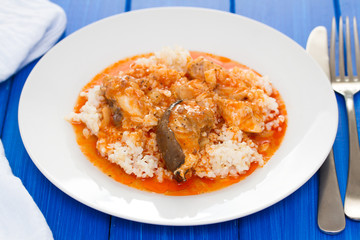 fish stew with rice on white plate on wooden background