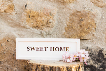 sweet home sign on a wood trunk. Stone wall background