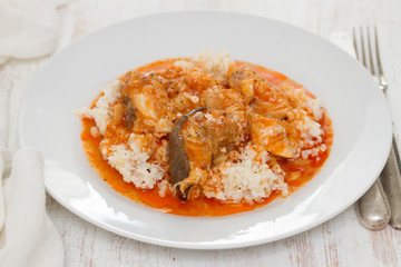 fish stew with rice on white plate on wooden background