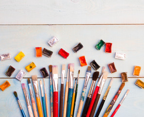 Paints, brushes on the white wood background. The workplace of the artist. Banner for school