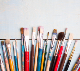 Obraz premium Brushes on the blue wood background. The workplace of the artist. Banner for school
