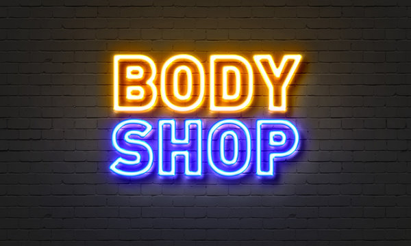 Body shop neon sign on brick wall background.