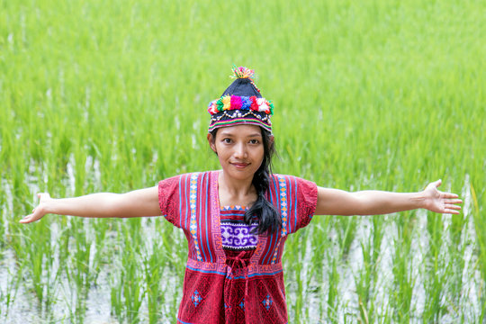 Asian woman in traditional costume for Karen show green rice field