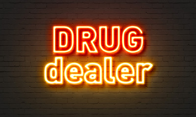 Drug dealer neon sign on brick wall background.