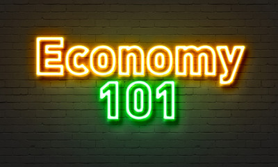 Economy 101 neon sign on brick wall background.