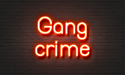 Gang crime neon sign on brick wall background.