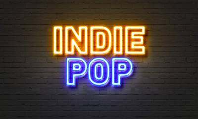 Indie pop neon sign on brick wall background.