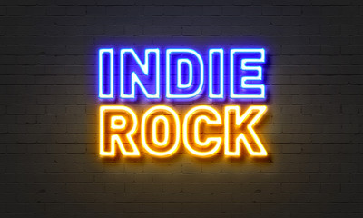 Indie rock neon sign on brick wall background.