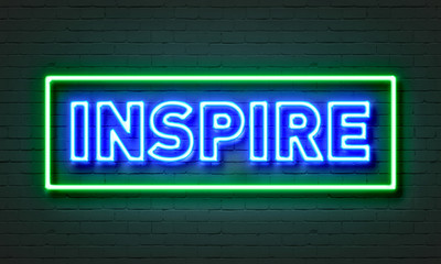 Inspire neon sign on brick wall background.