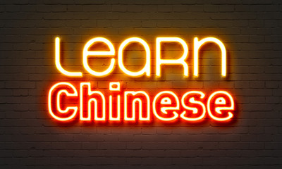 Learn Chinese neon sign on brick wall background.