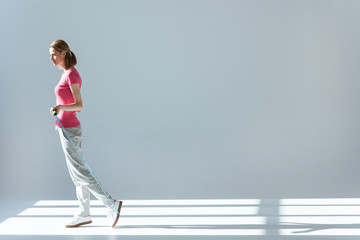 side view of sporty woman standing with skipping rope in hands