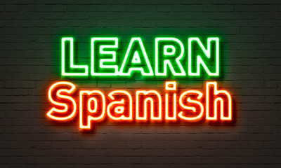 Learn Spanish neon sign on brick wall background.