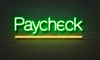 Paycheck neon sign on brick wall background.