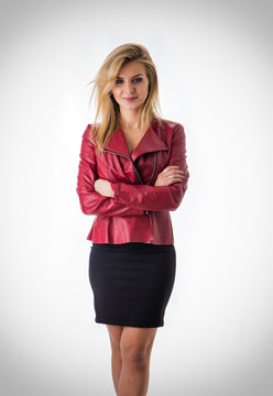 Portrait of attractive blonde woman in black skirt and red leather jacket looking at camera in studio shot