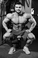 Fototapeta na wymiar Handsome fit caucasian muscular man flexing his muscles in gym