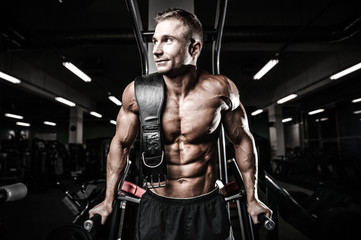 Fototapeta na wymiar Brutal bodybuilder powerful training arms, pectorals and shoulders in gym