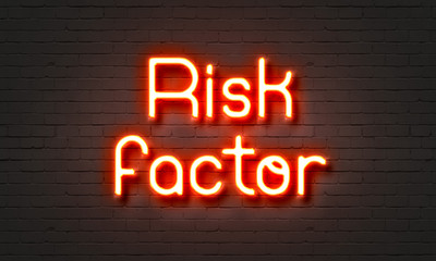 Risk factor neon sign on brick wall background.