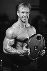 Fototapeta na wymiar Handsome fit caucasian muscular man flexing his muscles in gym