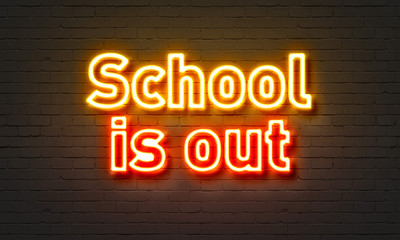 School is out neon sign on brick wall background.