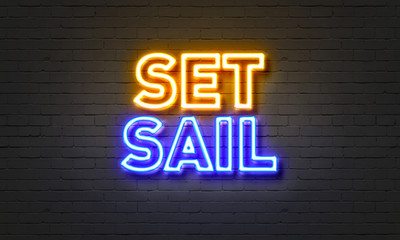 Set sail neon sign on brick wall background.