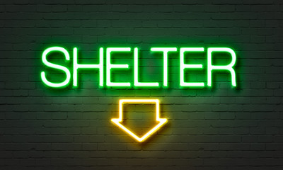 Shelter neon sign on brick wall background.