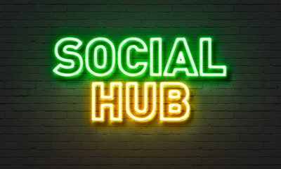 Social hub neon sign on brick wall background.