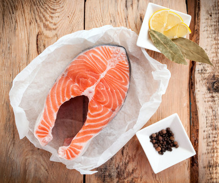 Raw salmon fish steak with lemon and spices on wooden rustic background. Fresh fish. Top view, copy space