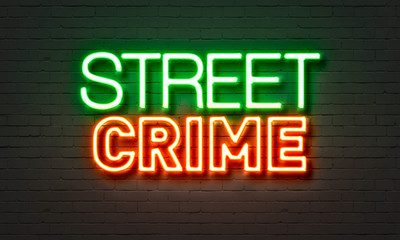 Street crime neon sign on brick wall background.