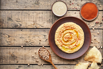 Hummus traditional homemade eastern snack chickpea vegan natural nutrition lunch dip paste with paprika tahini and olive oil in clay plate on rustic flat lay. Healthy dietary fiber protein food