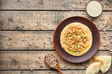 Hummus traditional homemade arabic chickpea vegan natural nutrition dip paste with pita paprika tahini parsley and olive oil in clay dish on rustic flat lay. Healthy dietary fiber protein food