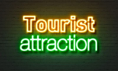 Tourist attraction neon sign on brick wall background.