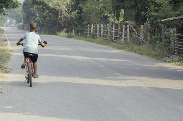 Boy riding a bicycle on a road in Thailand