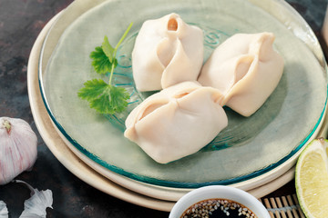 Uzbek dumplings (manti) with sauce and black chopsticks on glass plate