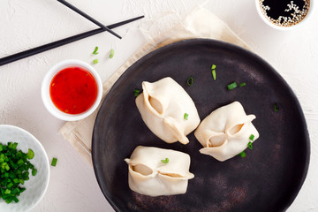 Uzbek dumplings (manti) with sauce and black chopsticks on white background