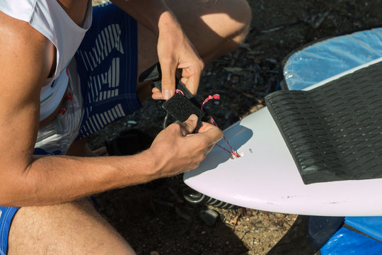 Boy Setting Up His White Board before Surfing in the Sea