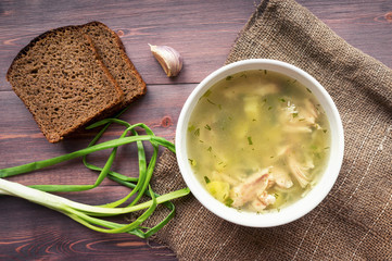 Chicken soup on wooden table.