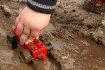 A child plays with a toy in the spring mud