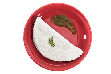 Delicious Tapioca, a brazilian snack made with cassava flour and stuffed with chicken and zucchini on a red plate isolated on white background