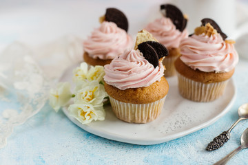 Vanilla cupcakes with chocolate chip cookies, decorated with flowers on a blue background(close-up)