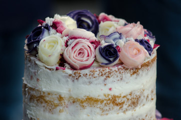 beautiful decorated cake with cream roses on dark background