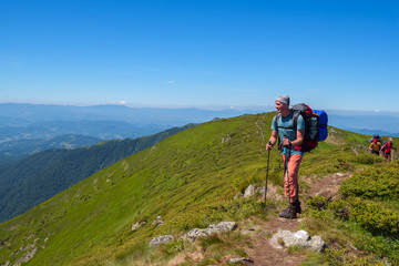 Fototapeta na wymiar Friends - men and boy with backpacks go on a mountain trail