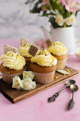 Cupcakes and flowers on a cutting Board on a pink background (close-up)