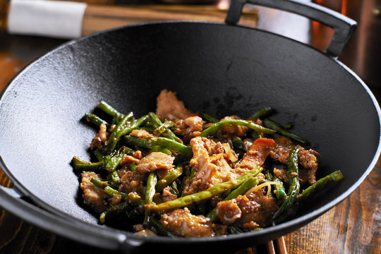 large cast iron wok with chicken and stringbean stirfry