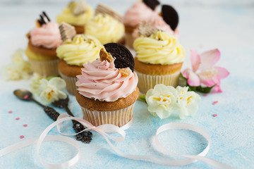 Spring cupcakes with pink and yellow cream on light background