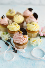 Delicious spring cupcakes with pink and yellow cream on light background