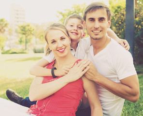 smiling family of three on green meadow .