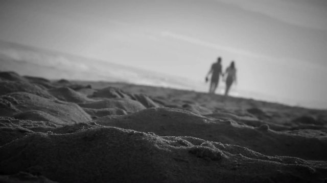 Artistic shot of couple walking by the beach shore Black and white